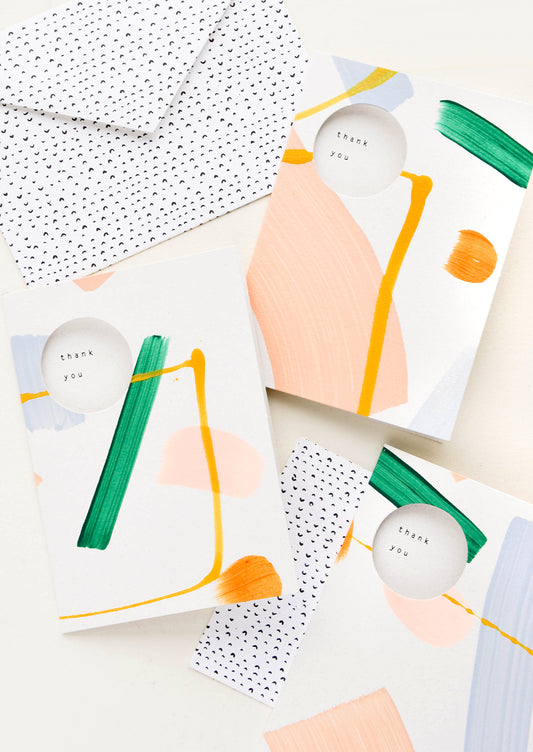 Hand painted thank you cards with abstract paint strokes. Circle cutouts on front with "Thank you" printed inside card.