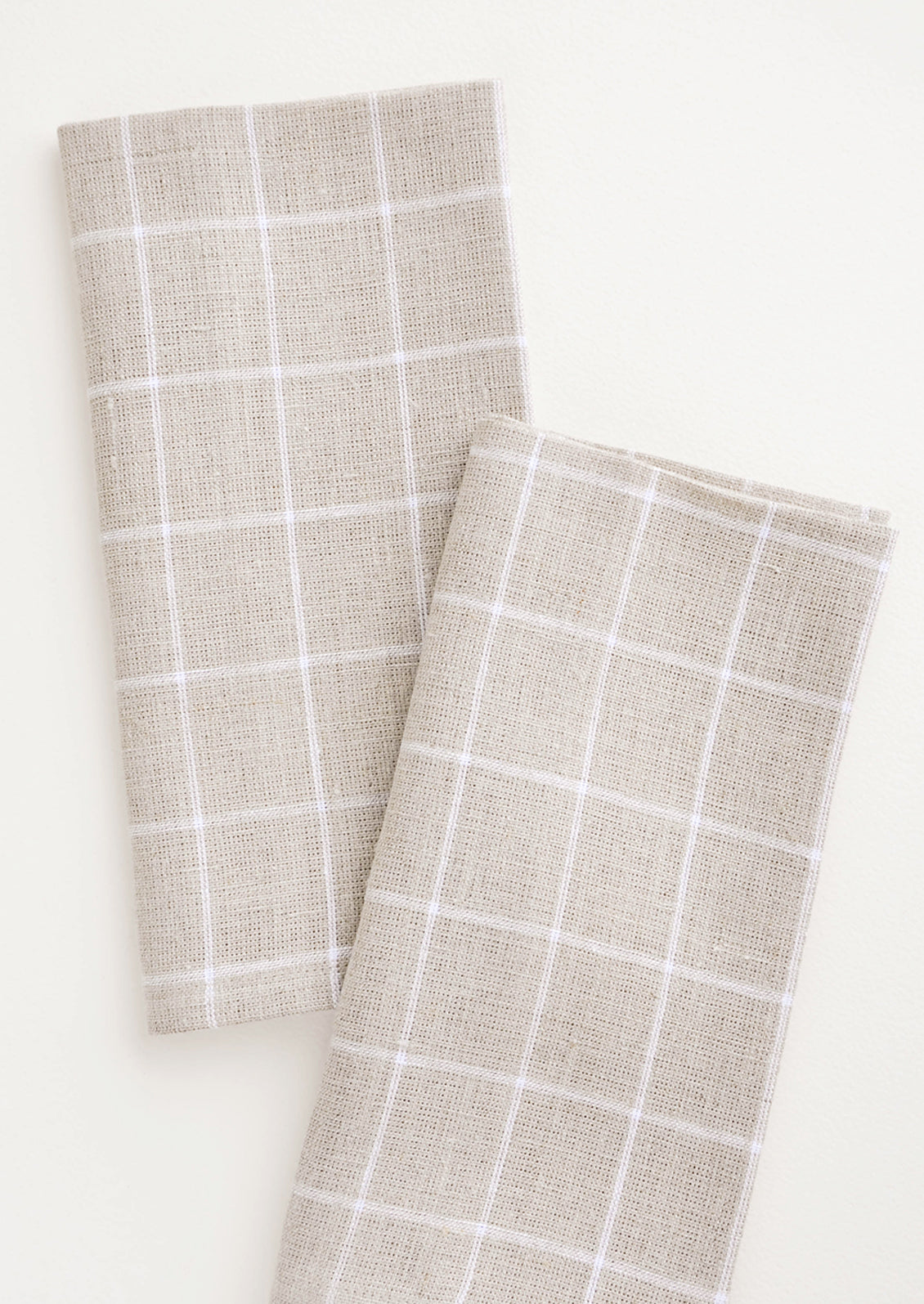 Pair of fabric dinner napkins in beige and white grid pattern
