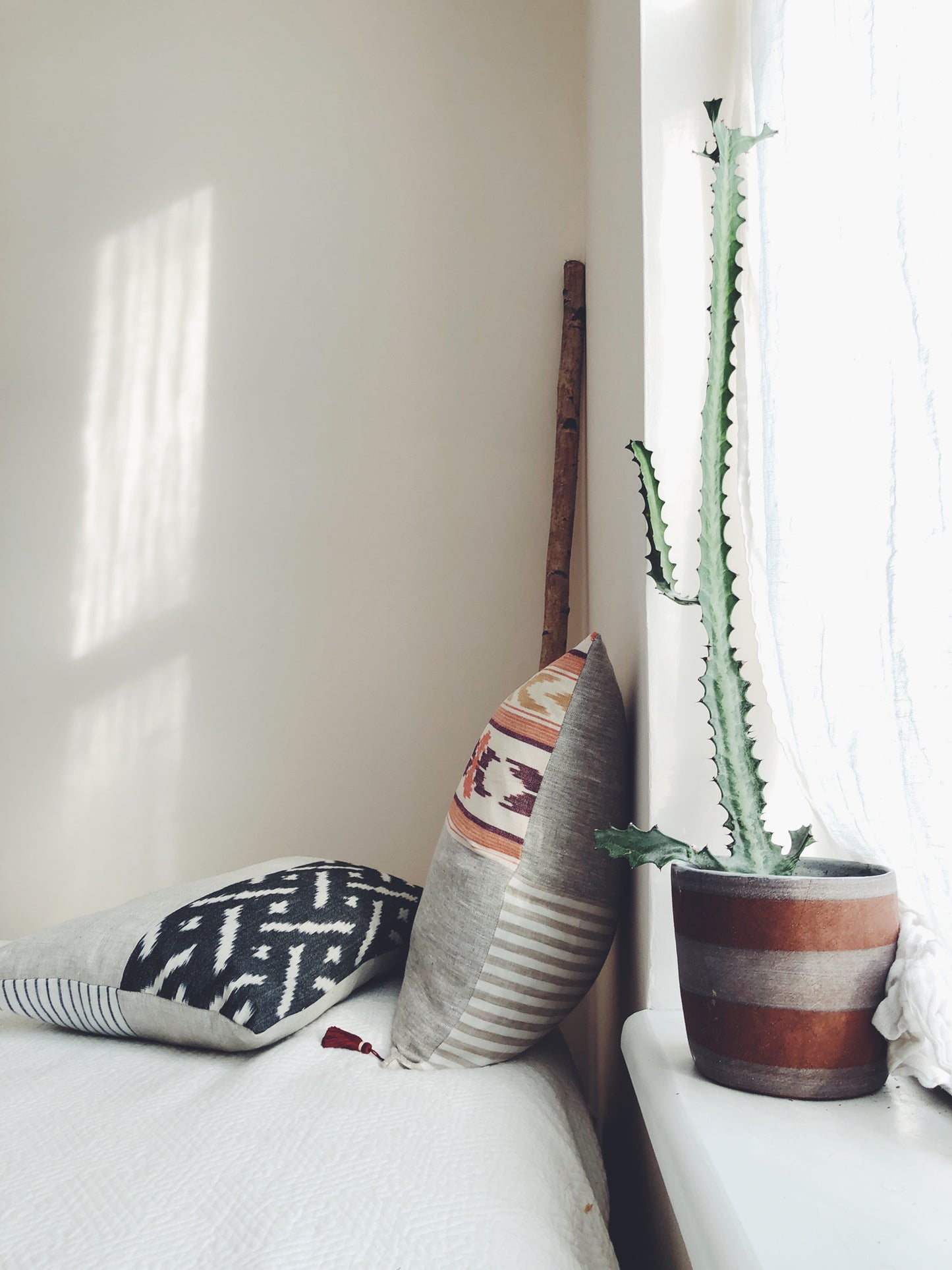A softly lit room with throw pillows effortlessly displayed on white bedsheets