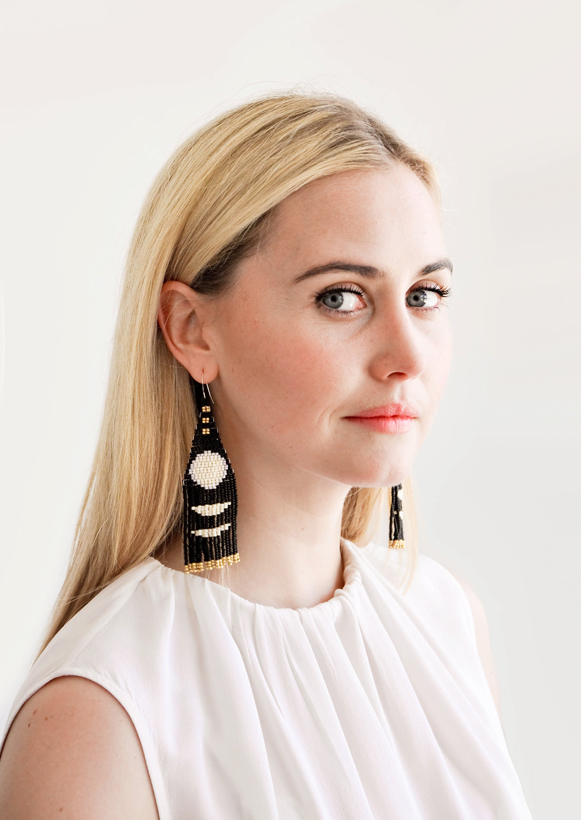 Model shot showing woman wearing beaded earrings and white top.