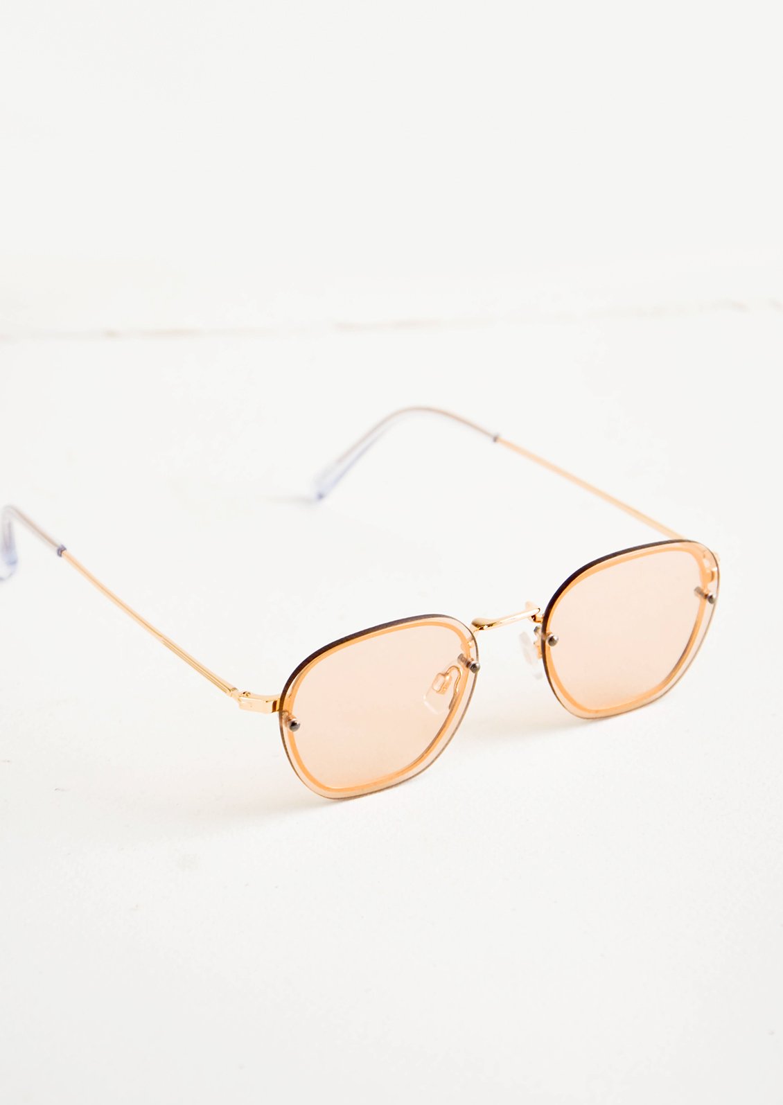 Sunglasses with light tan tinted plastic lenses and a metal frame behind the lens