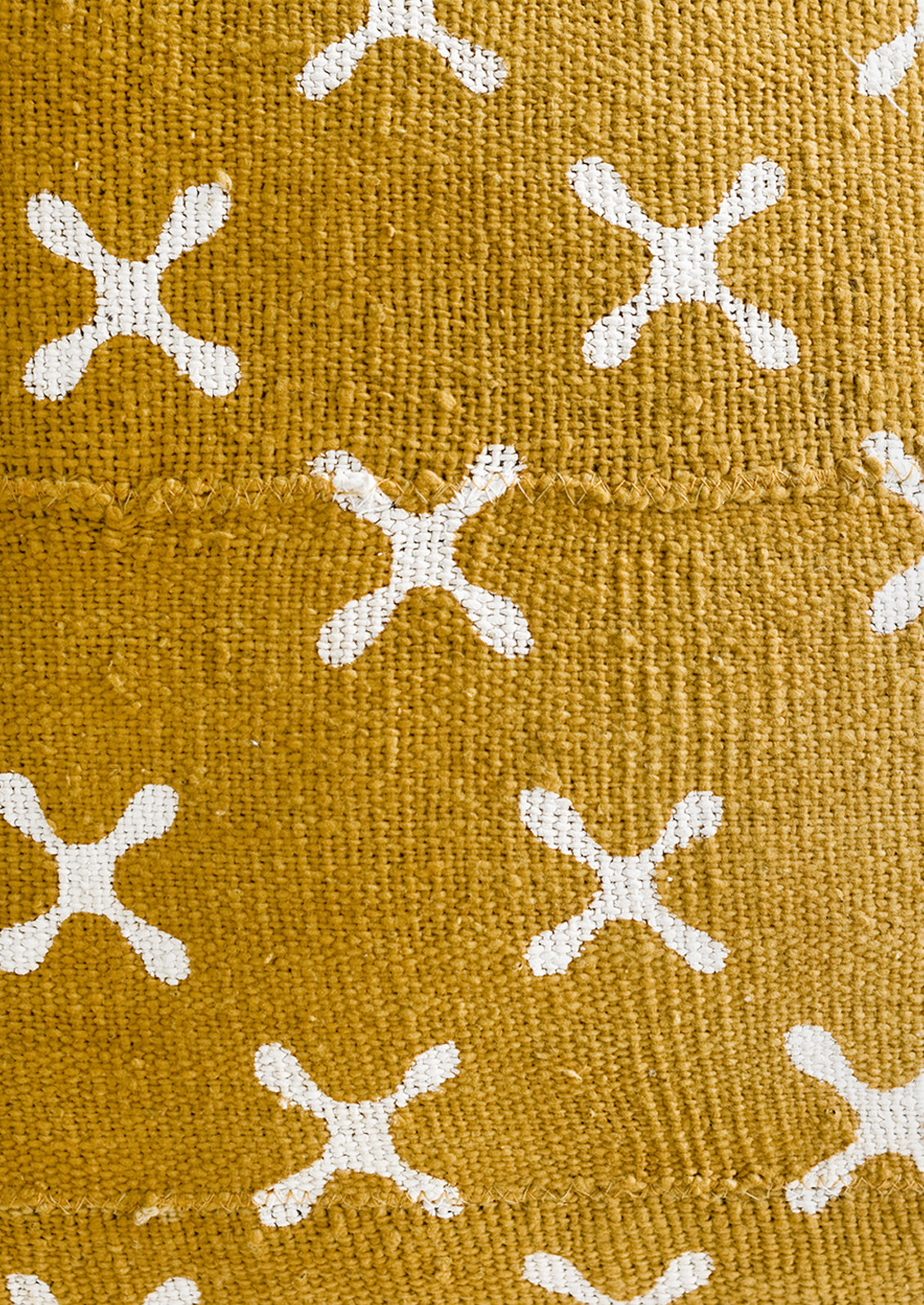 Mustard colored mudcloth fabric with white X pattern.
