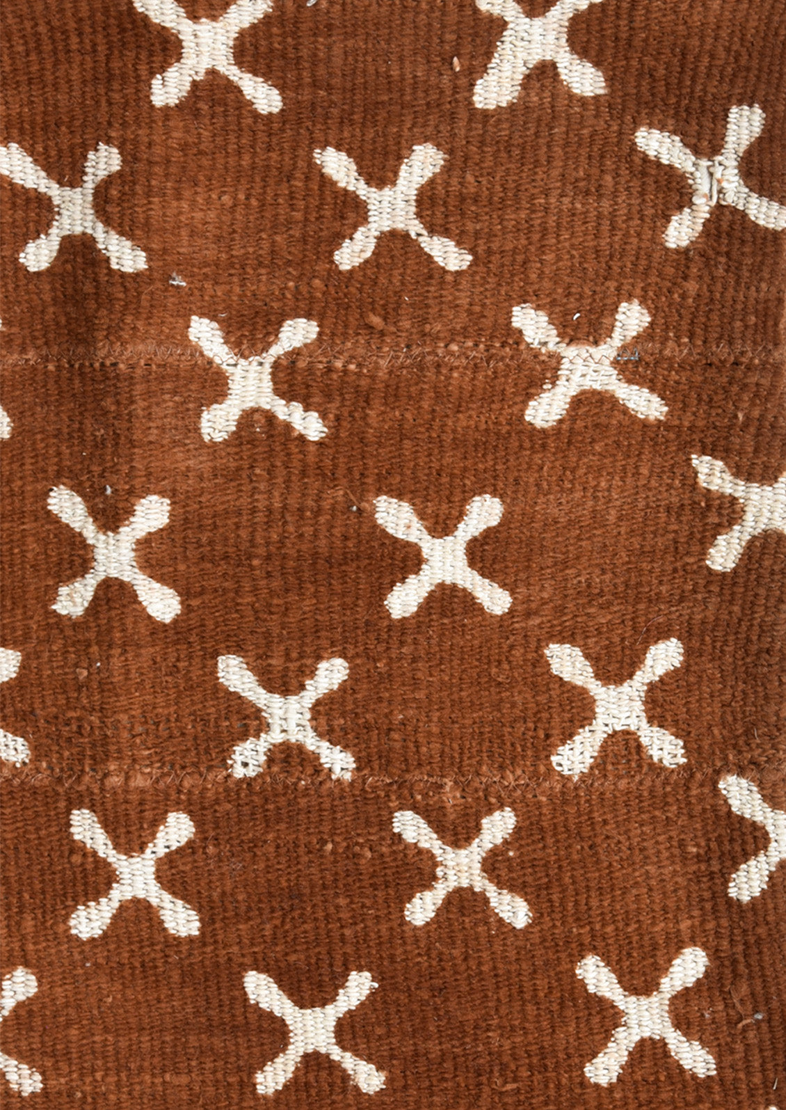 Rust colored mudcloth fabric with white X pattern.