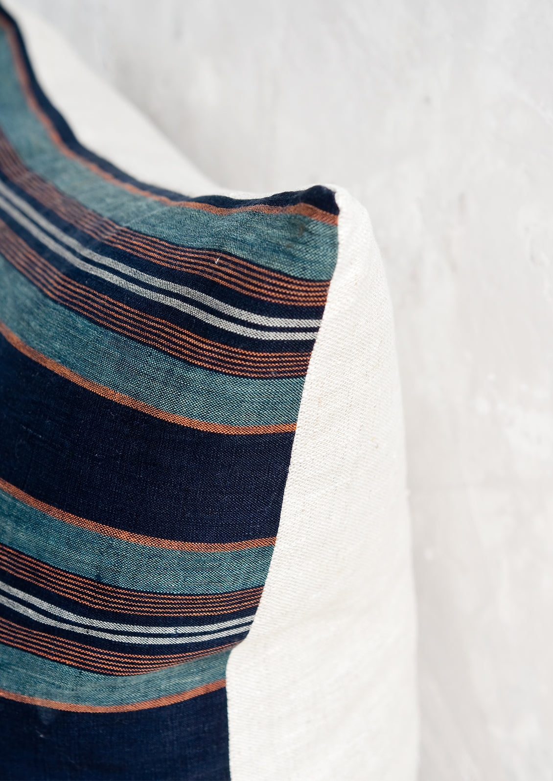 A striped throw pillow with natural linen back.