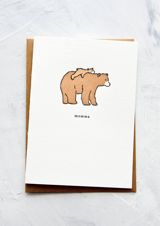 A letterpress printed greeting card with an image of a baby bear laying on back of larger bear. Text underneath reads "momma".