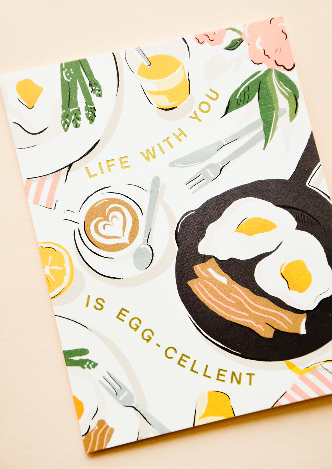 Greeting card with breakfast scene and gold letters reading "Life with you is egg-cellent"