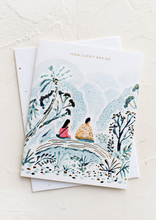A greeting card with image of couple sitting on a bridge, text above reads "How lucky are we".