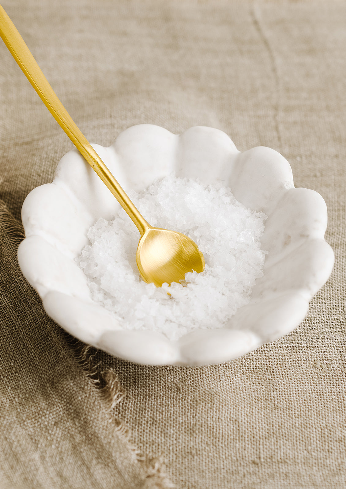 A small white ceramic flower shaped bowl with salt.