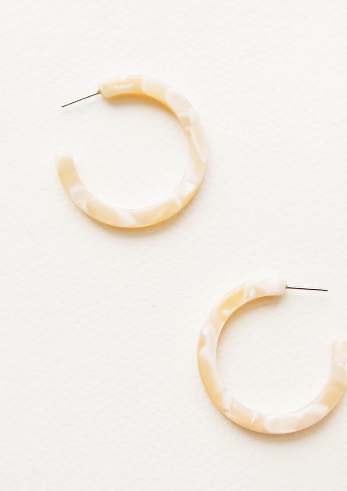 Three quarter hoop earrings in marbled ivory and beige acetate.