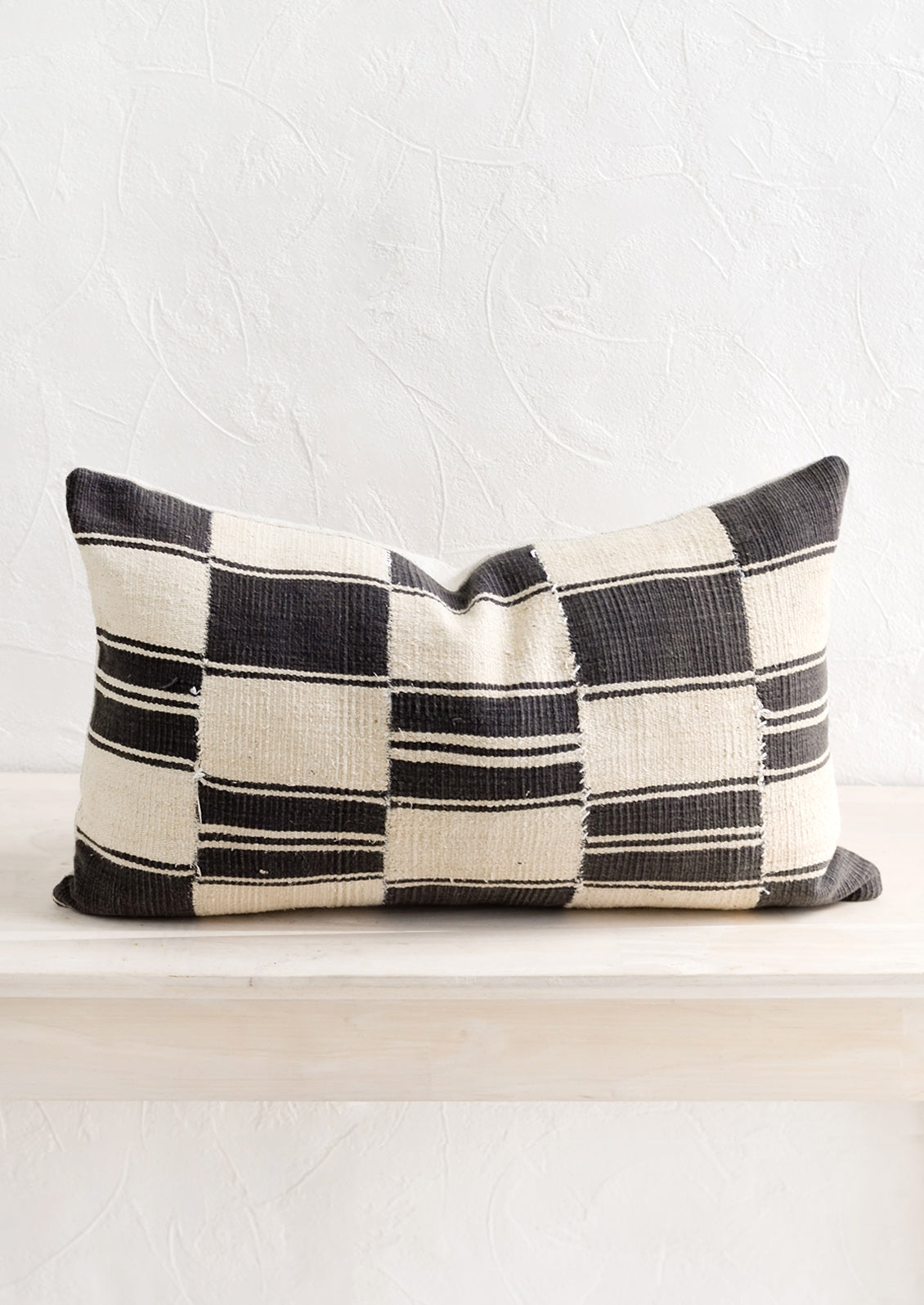 A throw pillow made from vintage African black and white fabric.