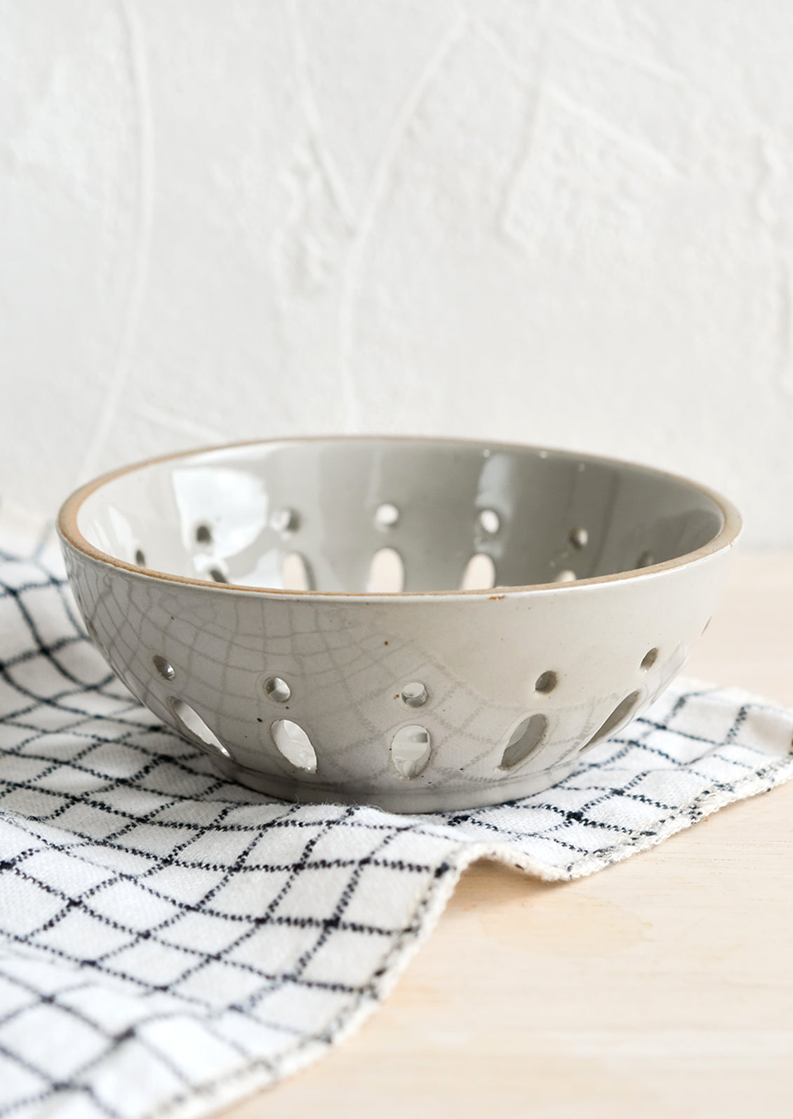 A ceramic berry bowl with drainage holes in pale grey.