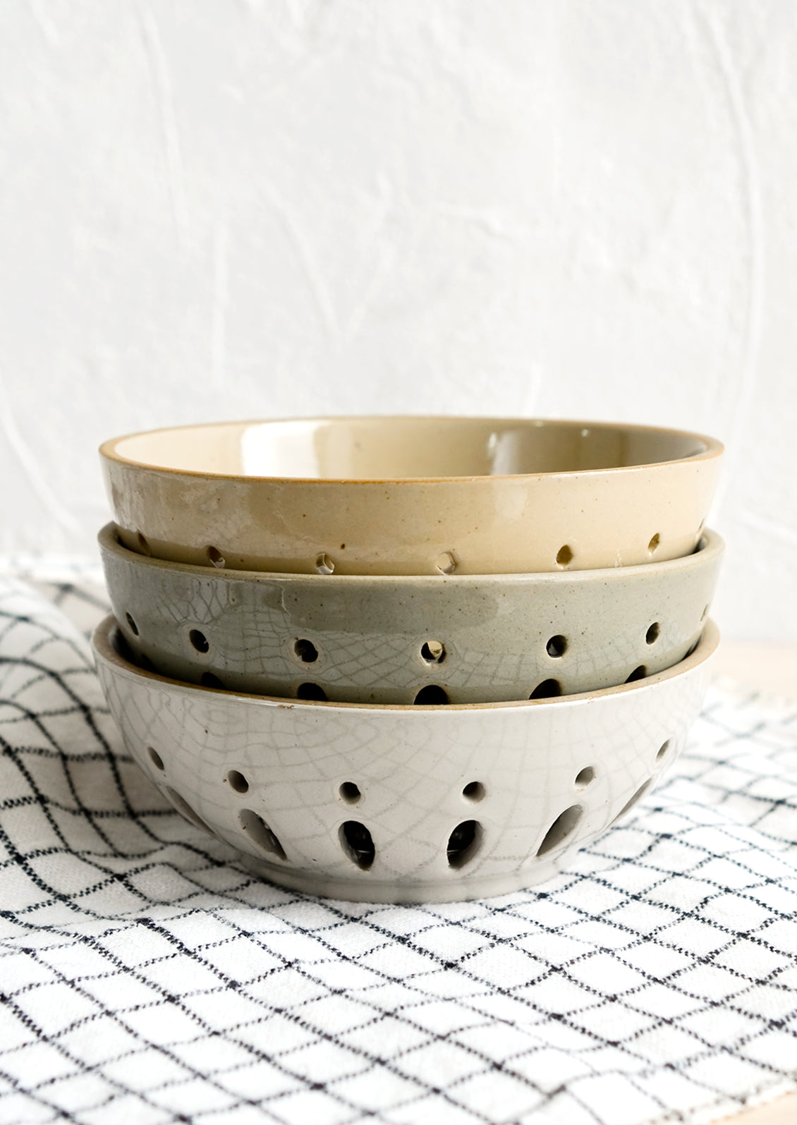 A stack of three ceramic berry bowls/colanders.