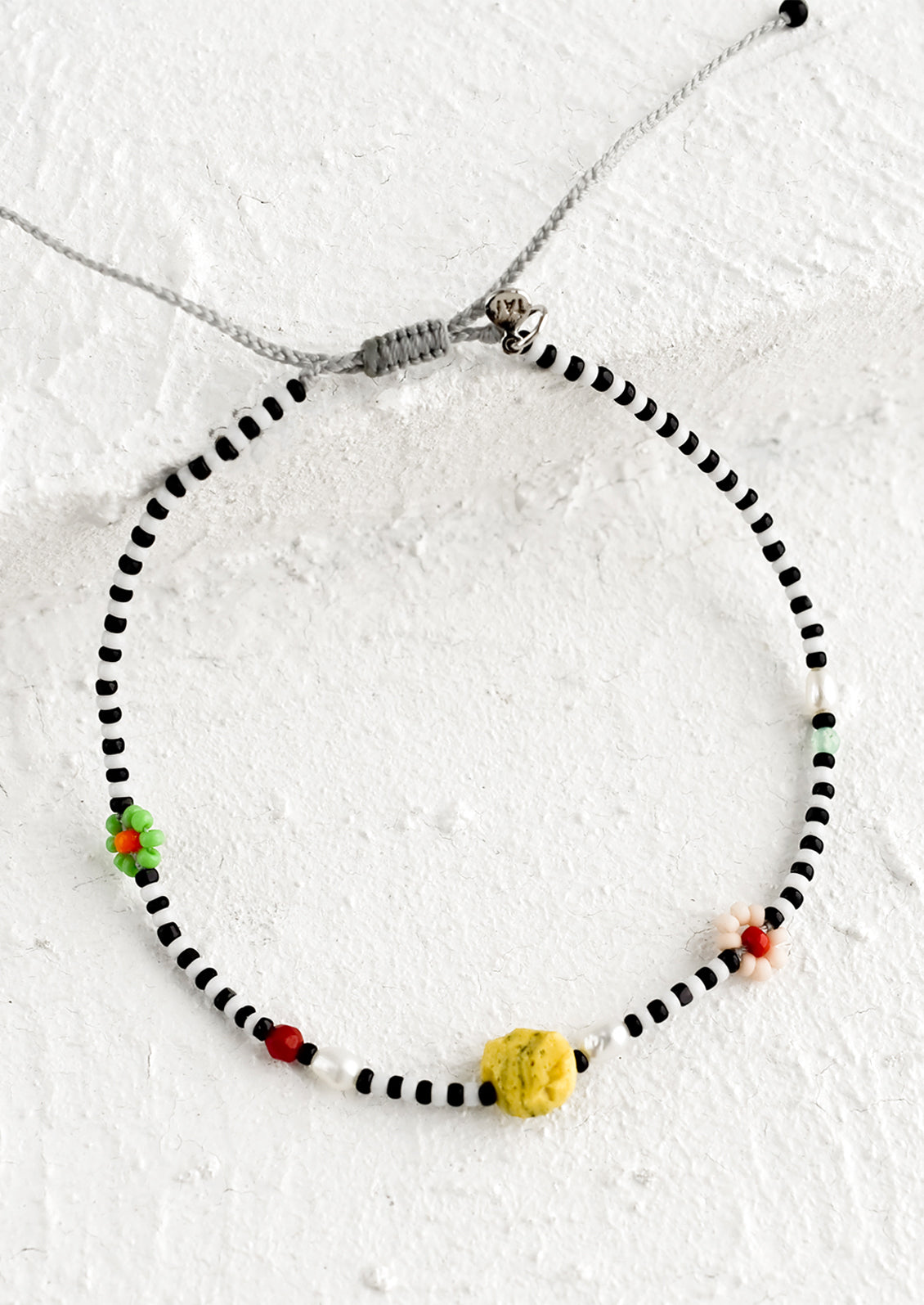 A black and white seed bead bracelet with mixed flower and gemstone beads.