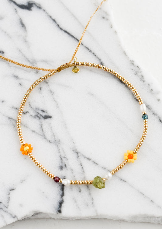 A gold seed bead bracelet with mixed flower and gemstone beads.
