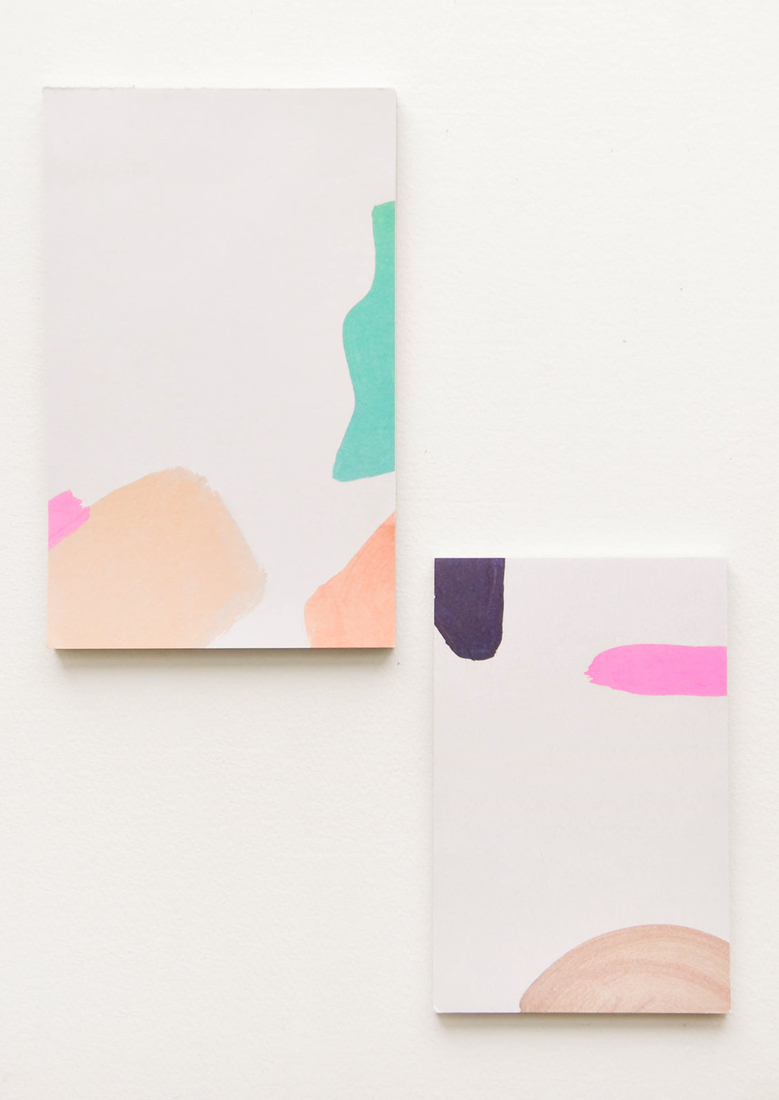 Two notepads, decorated with colorful abstract shapes.
