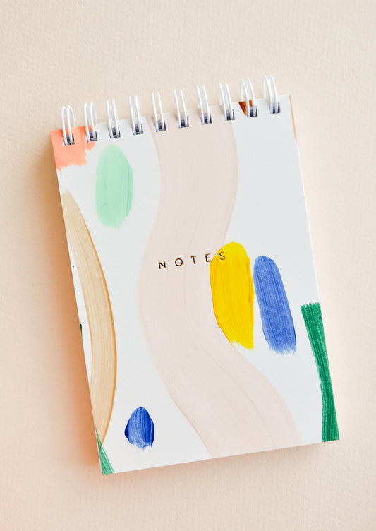 Small spiral bound notepad with cover decorated in colorful, hand-painted paint strokes