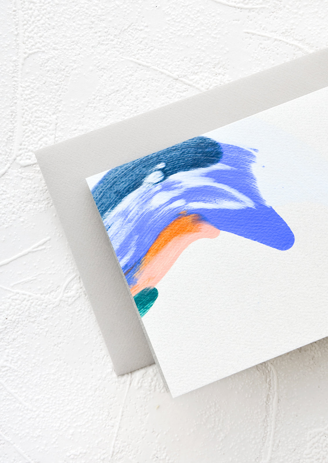 Folded grey greeting card with blue paint stroke detail and grey envelope