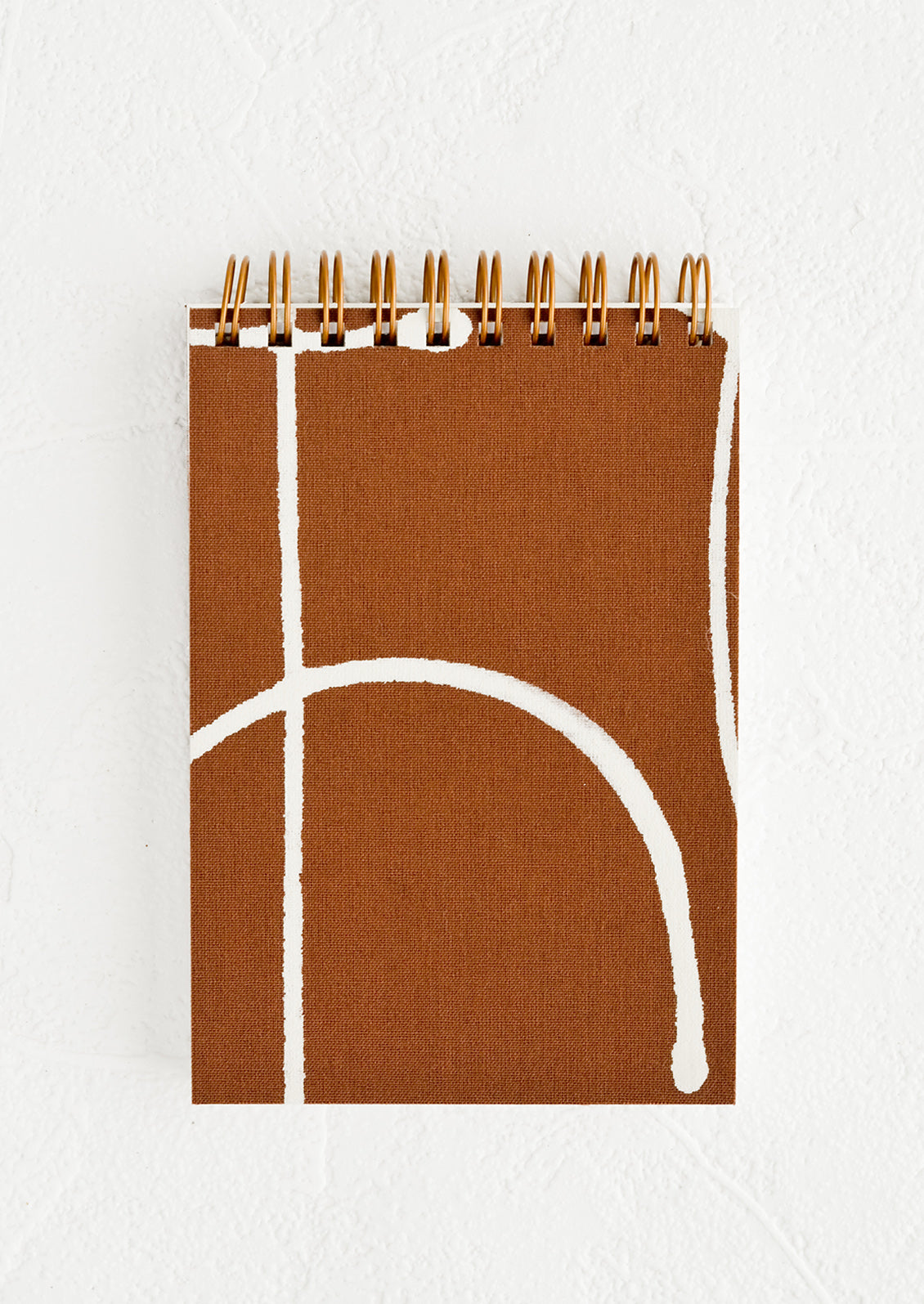 A small spiral bound pocket notebook with brown and white cover.