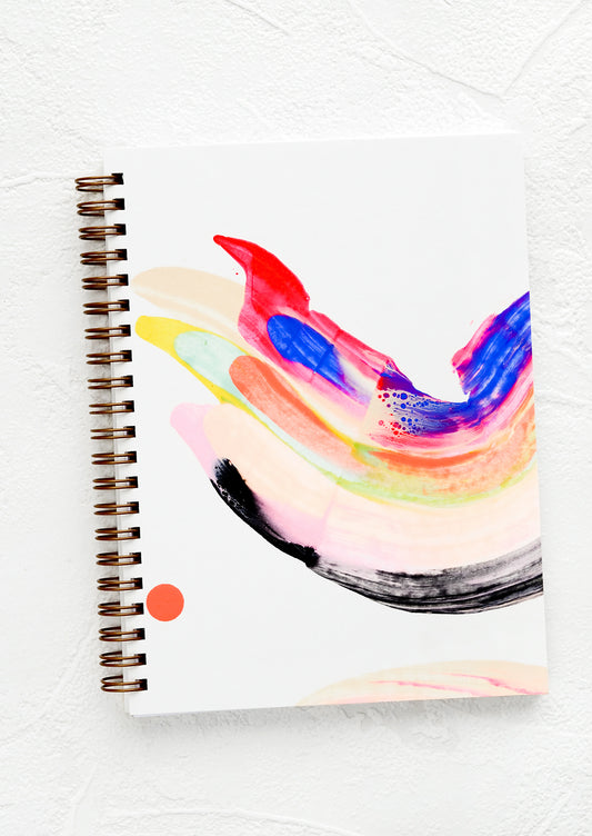 A hardcover, spiral bound notebook with a rainbow swirl, hand-painted cover.