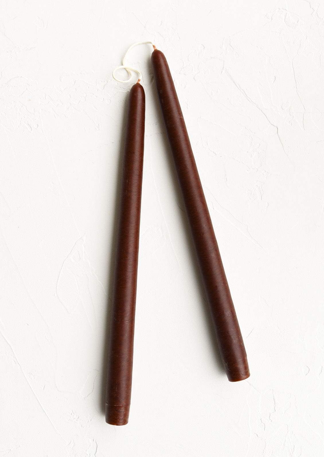 A pair of taper candles in dark brown