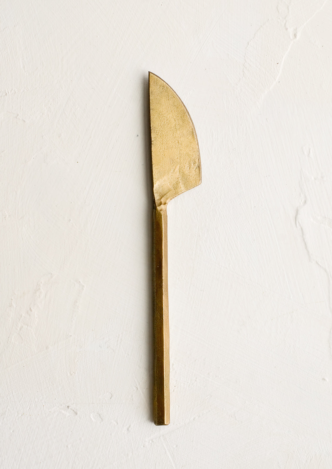 A canape sized knife with primitive inspired shape in brass.