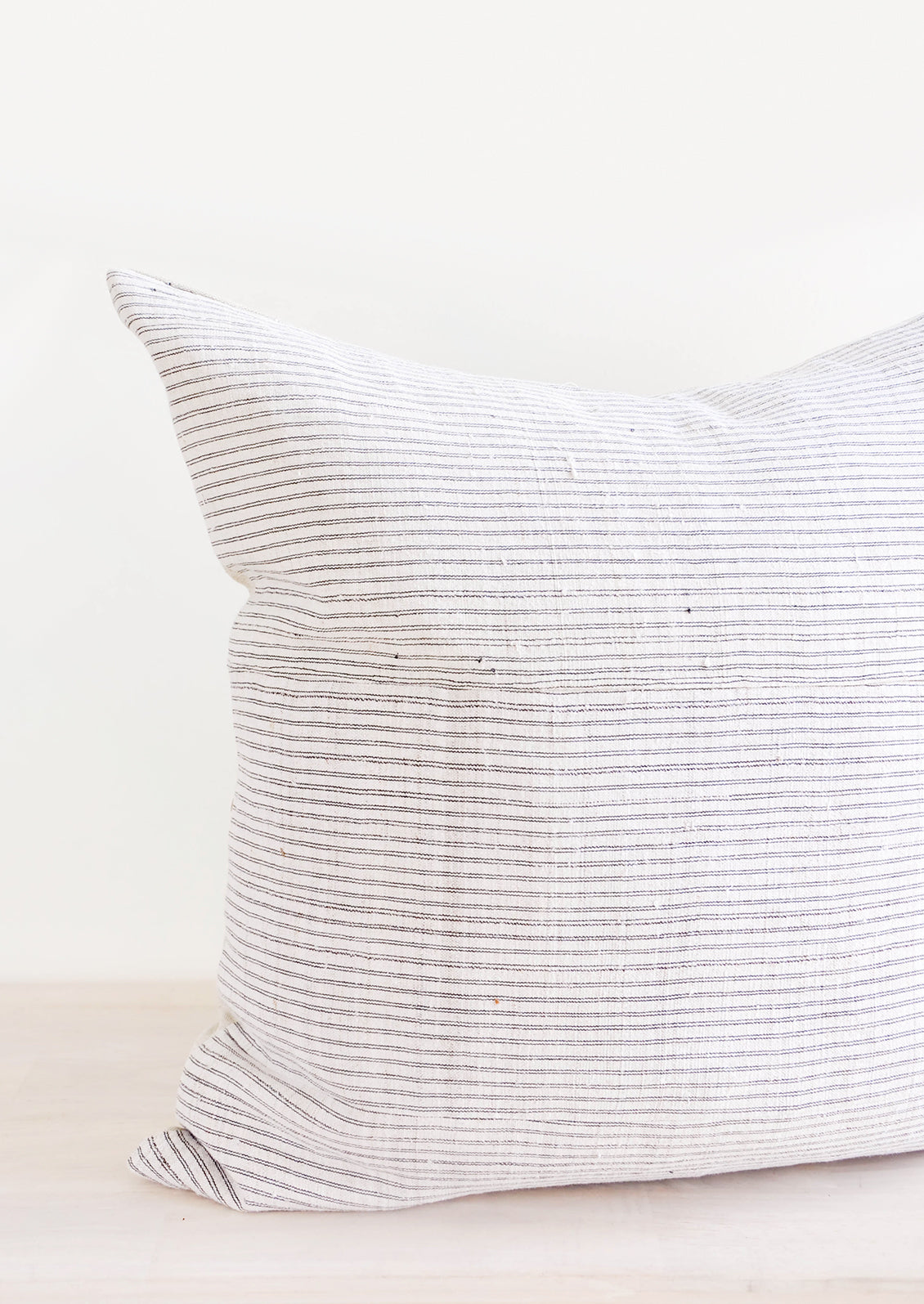 Square throw pillow in white hemp fabric with allover thin black stripes