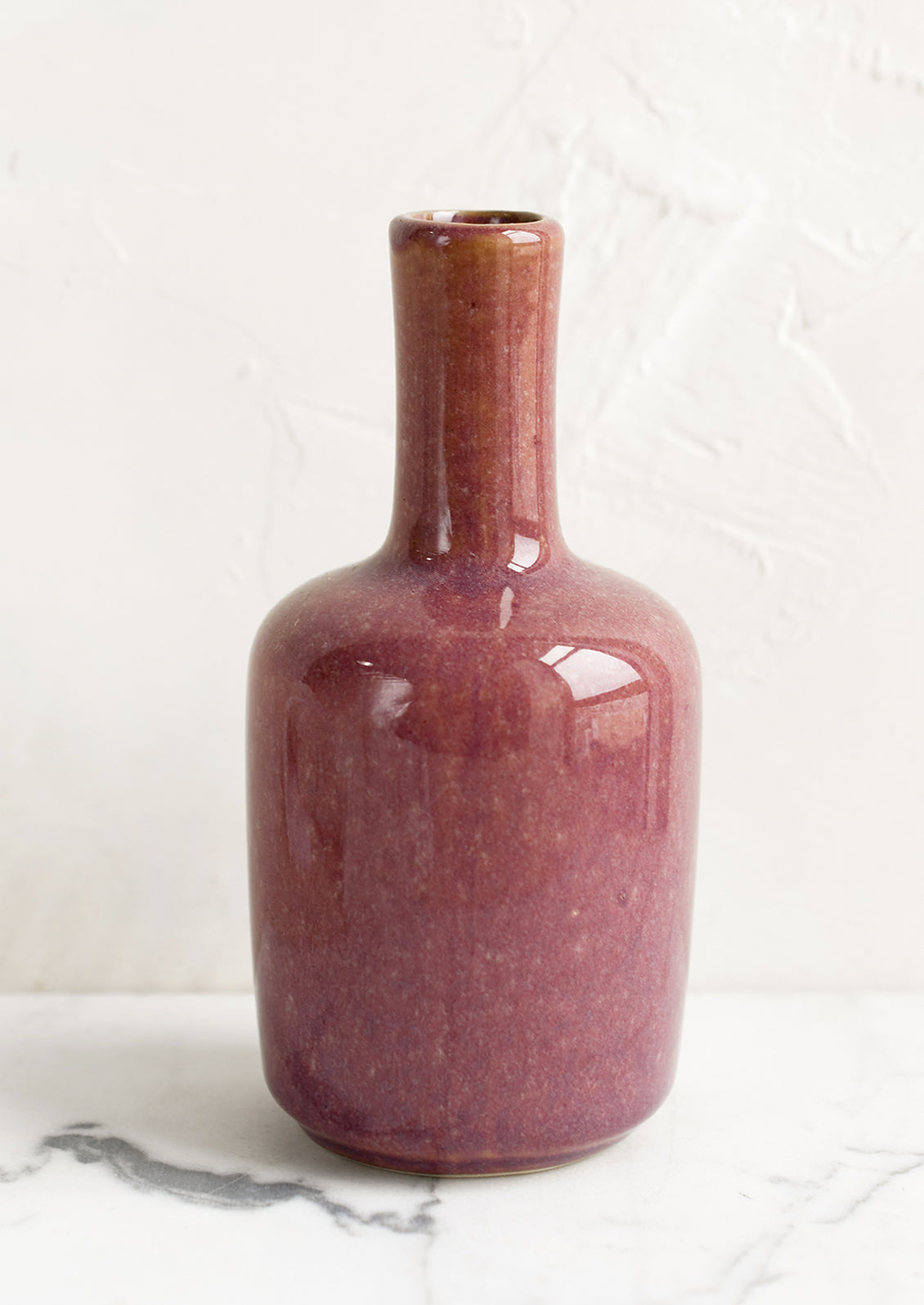 A ceramic bud vase in tall shape, elderberry color.
