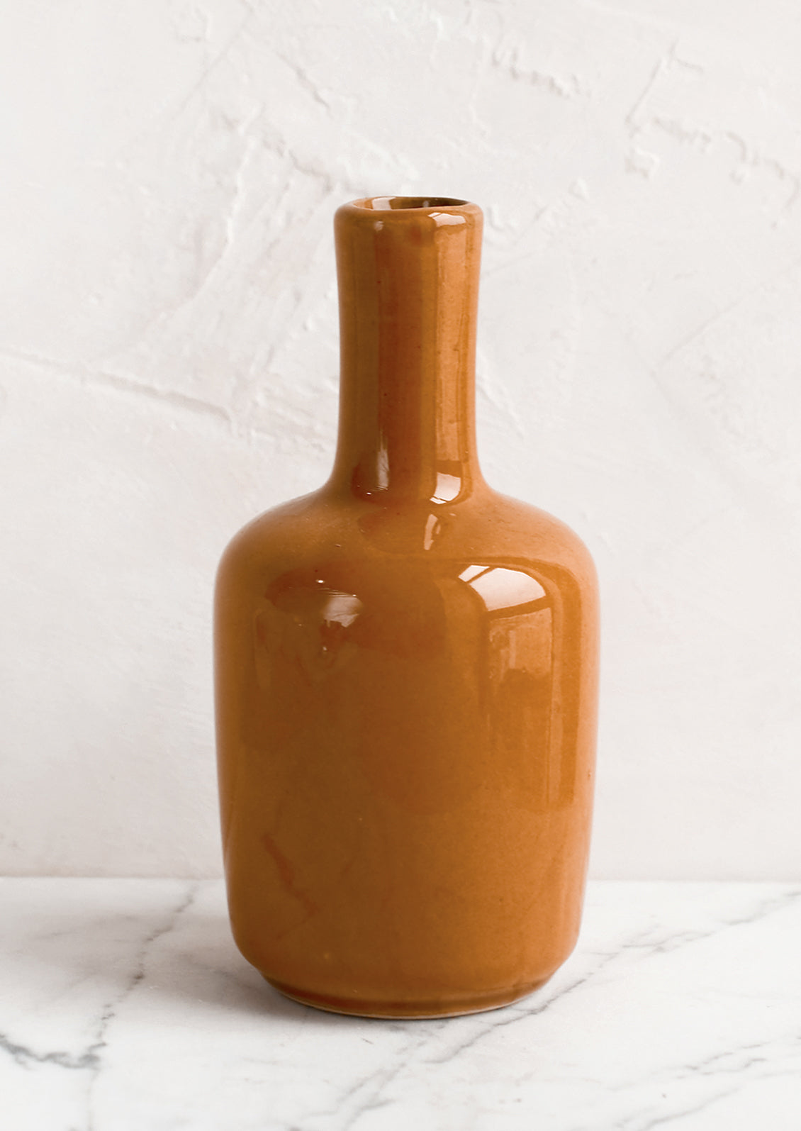 A ceramic bud vase in tall shape, turmeric color.