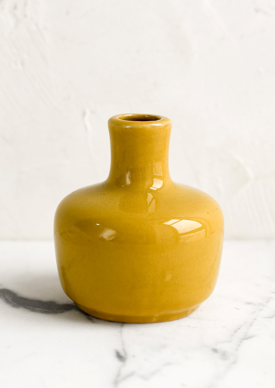 A ceramic bud vase in short shape, mustard color.