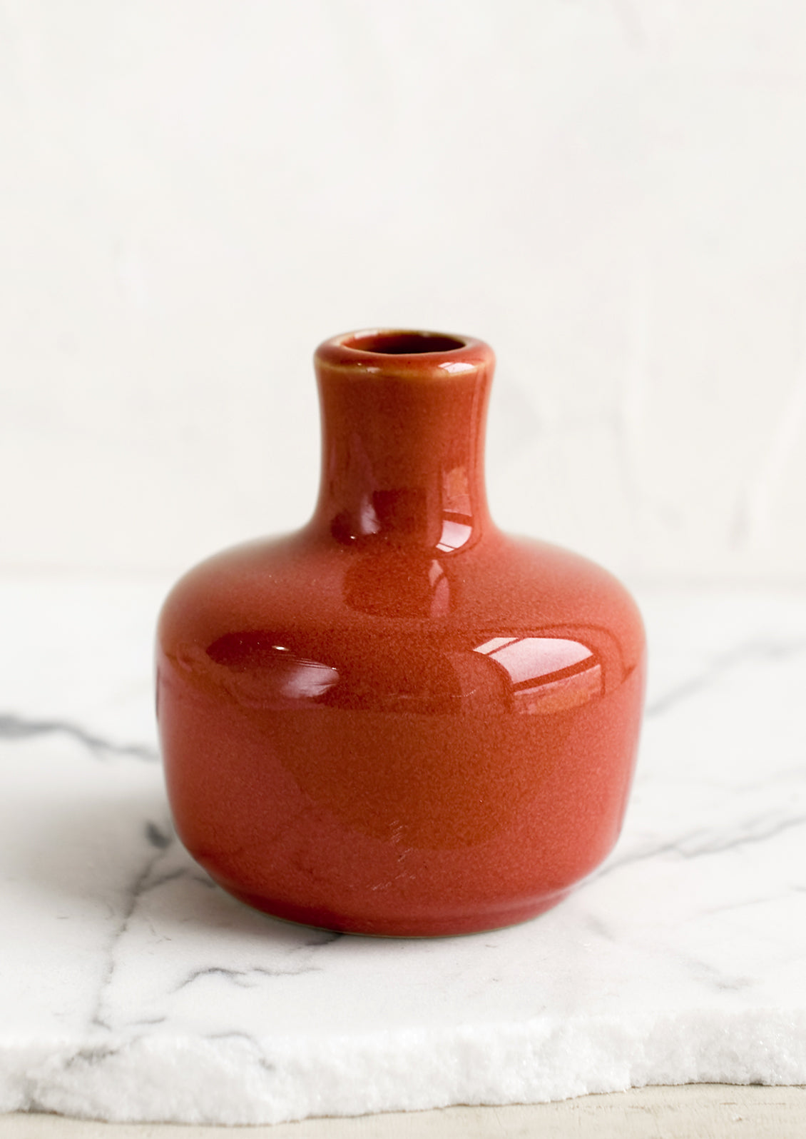 A ceramic bud vase in short shape, rhubarb color.