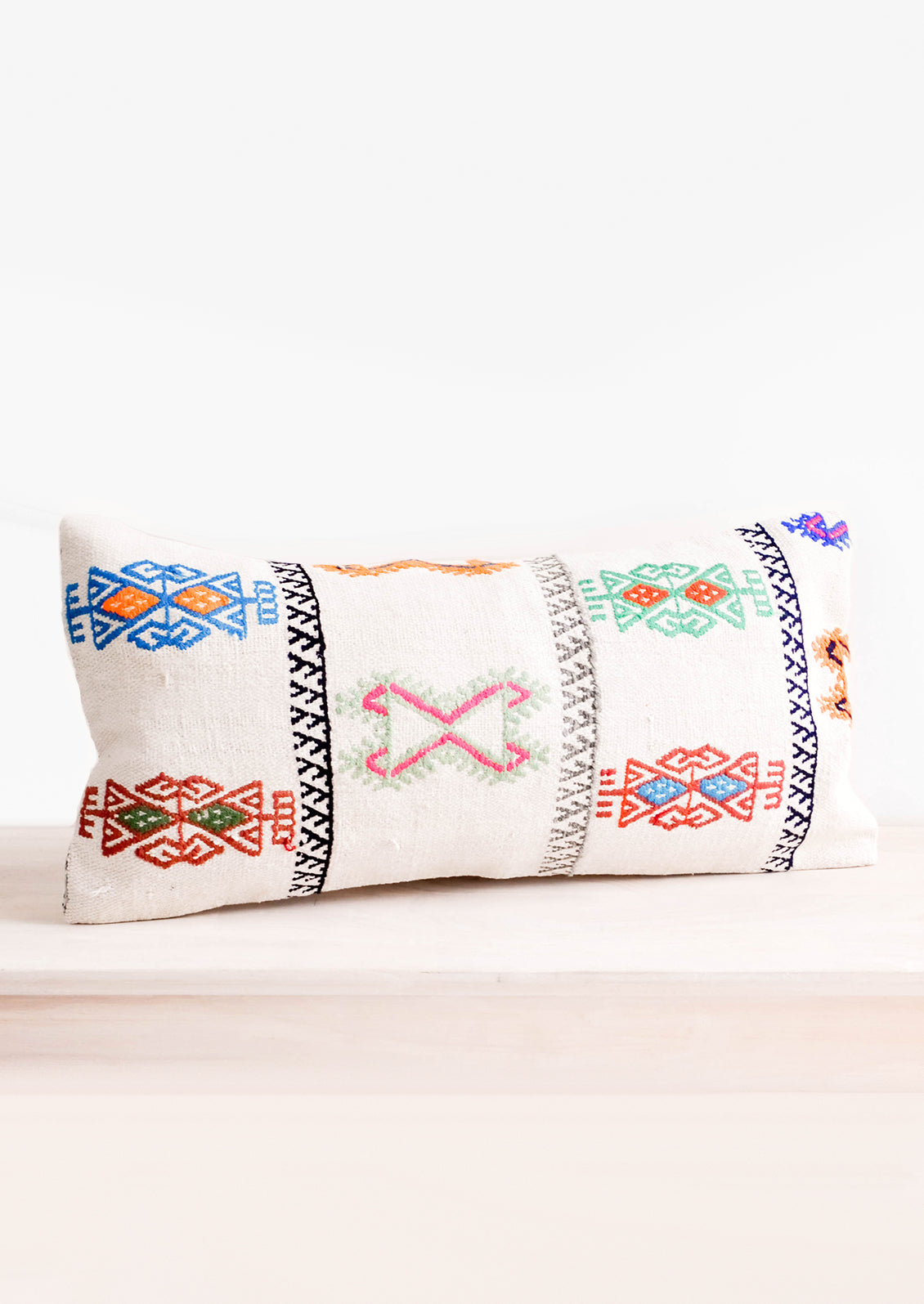 Rectangular throw pillow with neon embroidery on ivory background