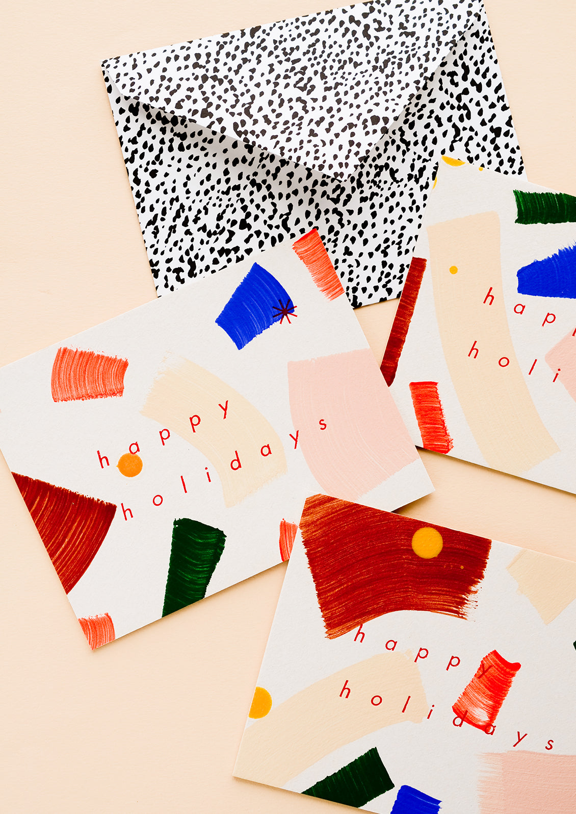 Three matching greeting cards with hand-painted brushstrokes and "happy holidays" in red lettering.