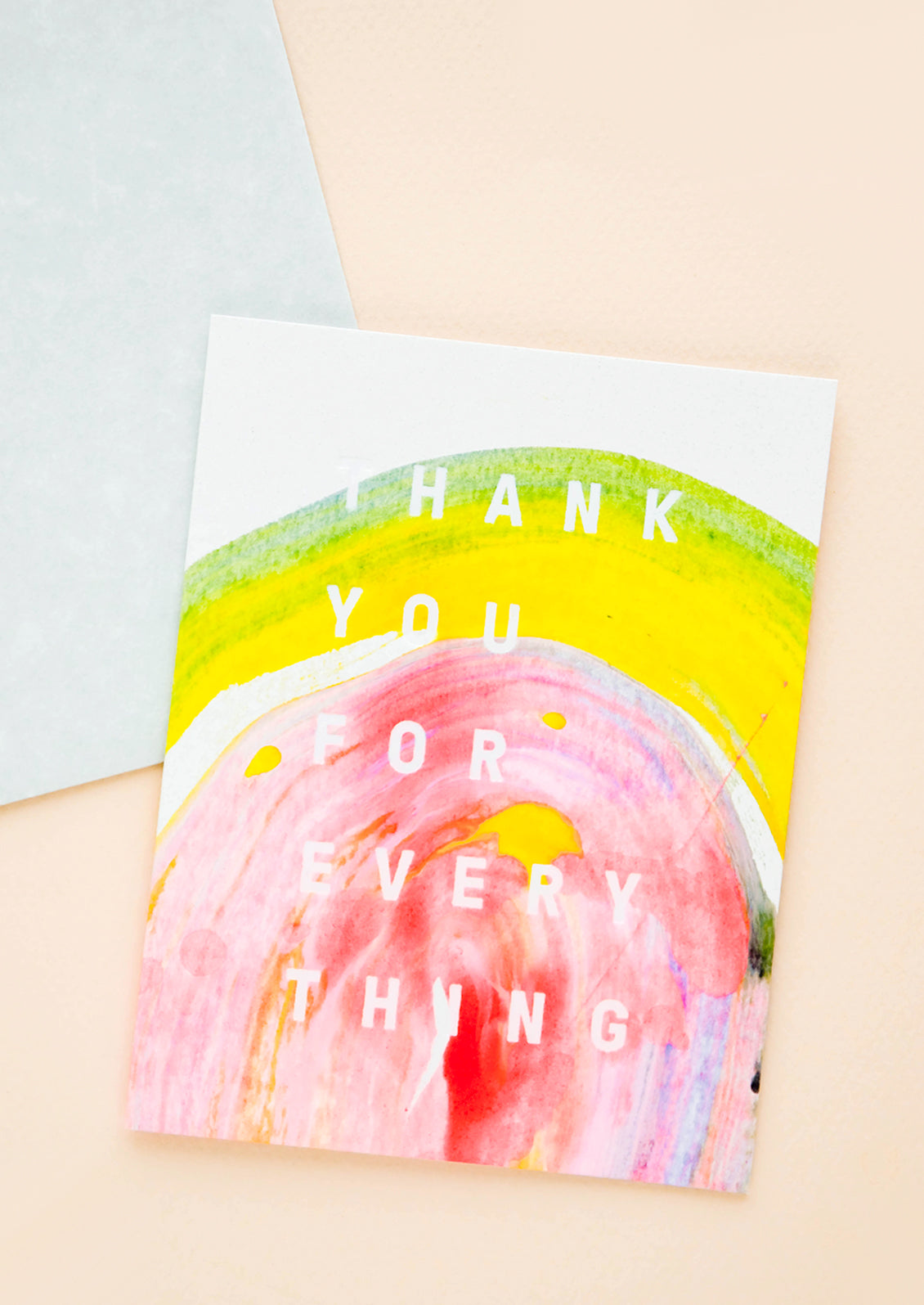 A greeting card featuring a sweep of multicolored paint in yellow and pink with white text reading "thank you for everything."