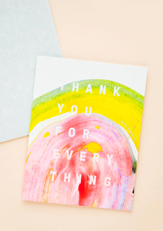 A greeting card featuring a sweep of multicolored paint in yellow and pink with white text reading "thank you for everything."
