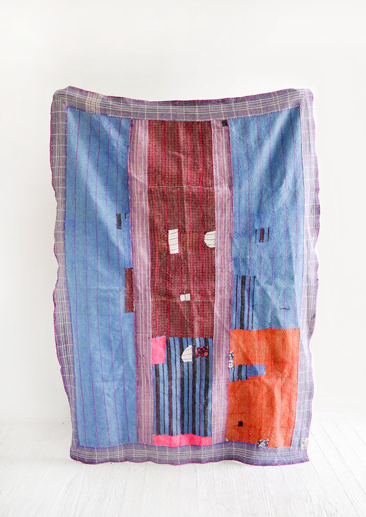 Vintage patchwork quilt in a mix of colors and fabrics. Predominantly blue, red and pink.