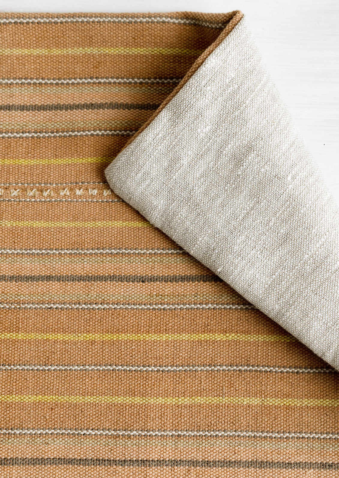 A throw pillow in clay stripe cotton fabric.