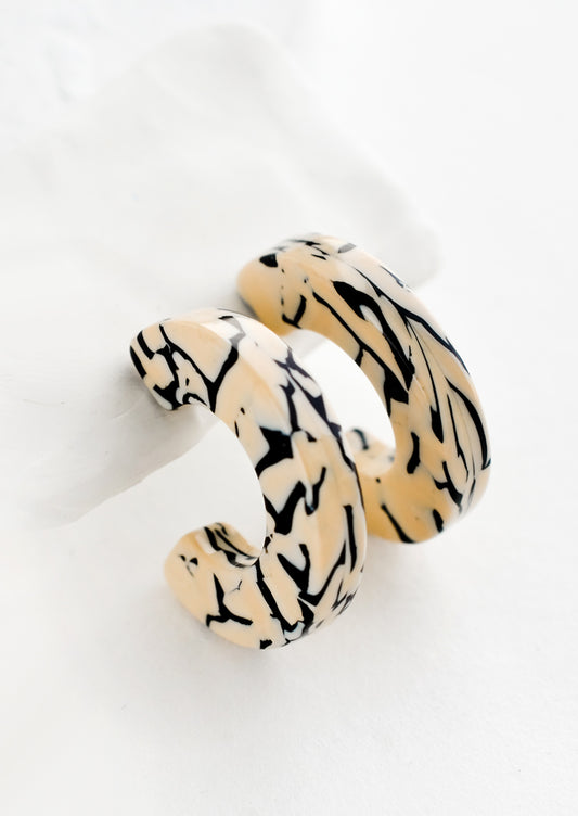 A pair of acetate hoop earrings in tan and black.