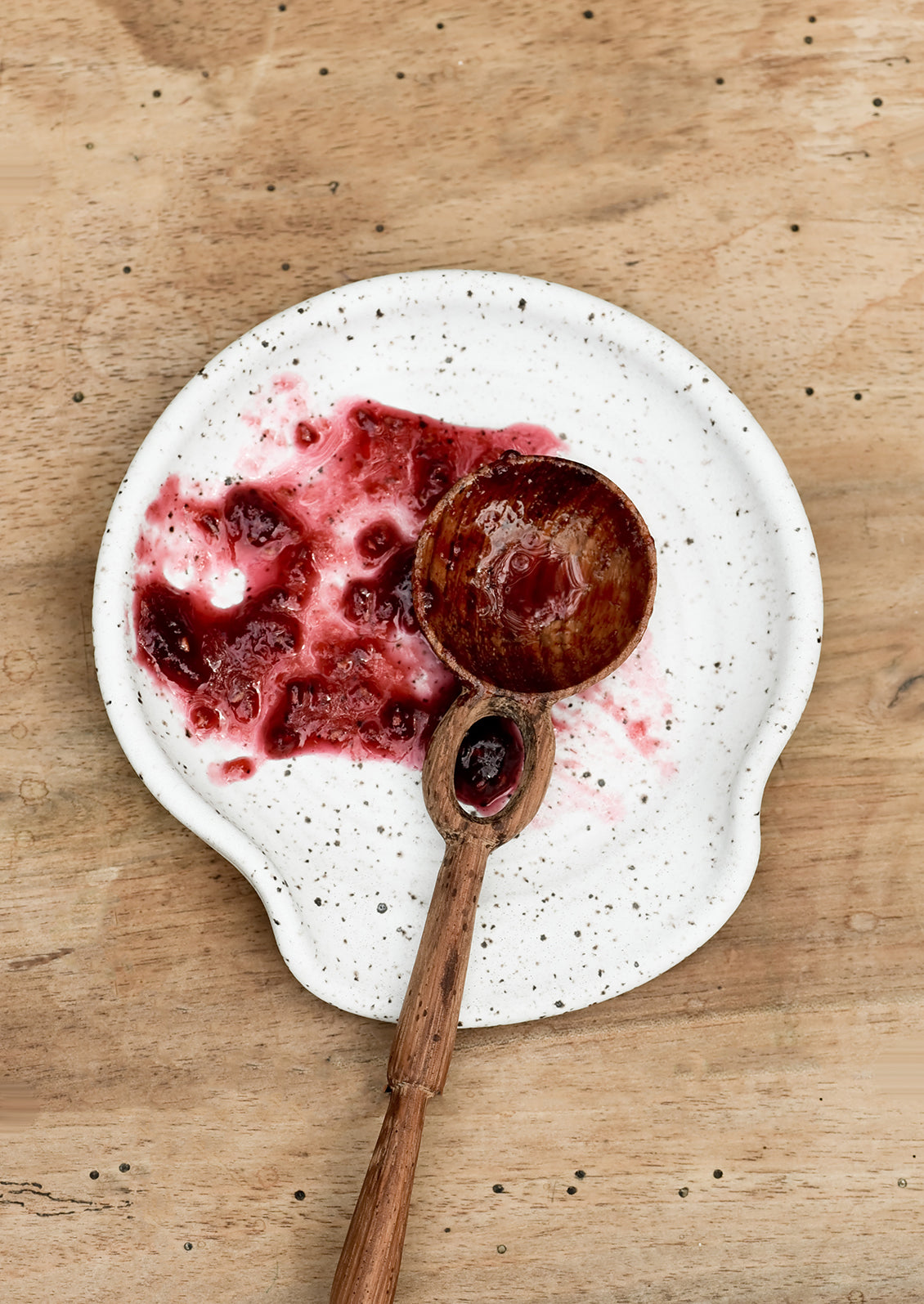 A spoon rest with spoon and raspberry jam.