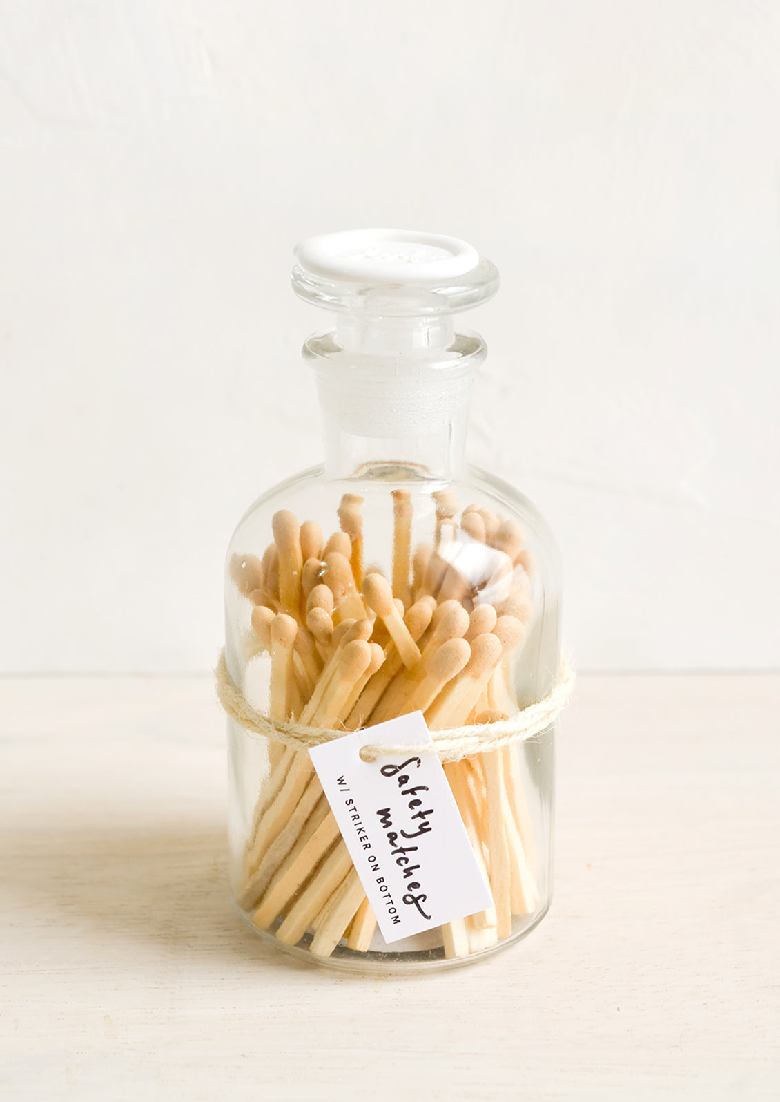 Safety matches with nude tips in a vintage-style glass apothecary jar with white wax seal on lid.