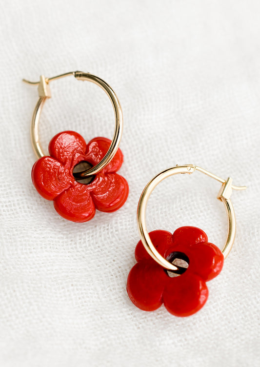 A pair of gold hoop earrings with single red flower bead.