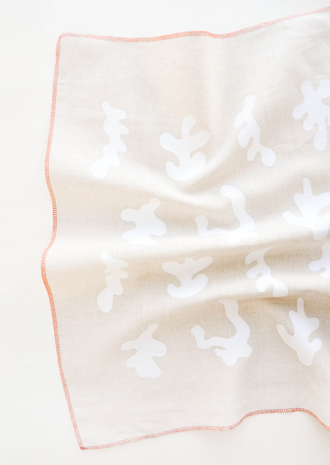 A crumpled beige towel with white squiggle pattern and orange trim.