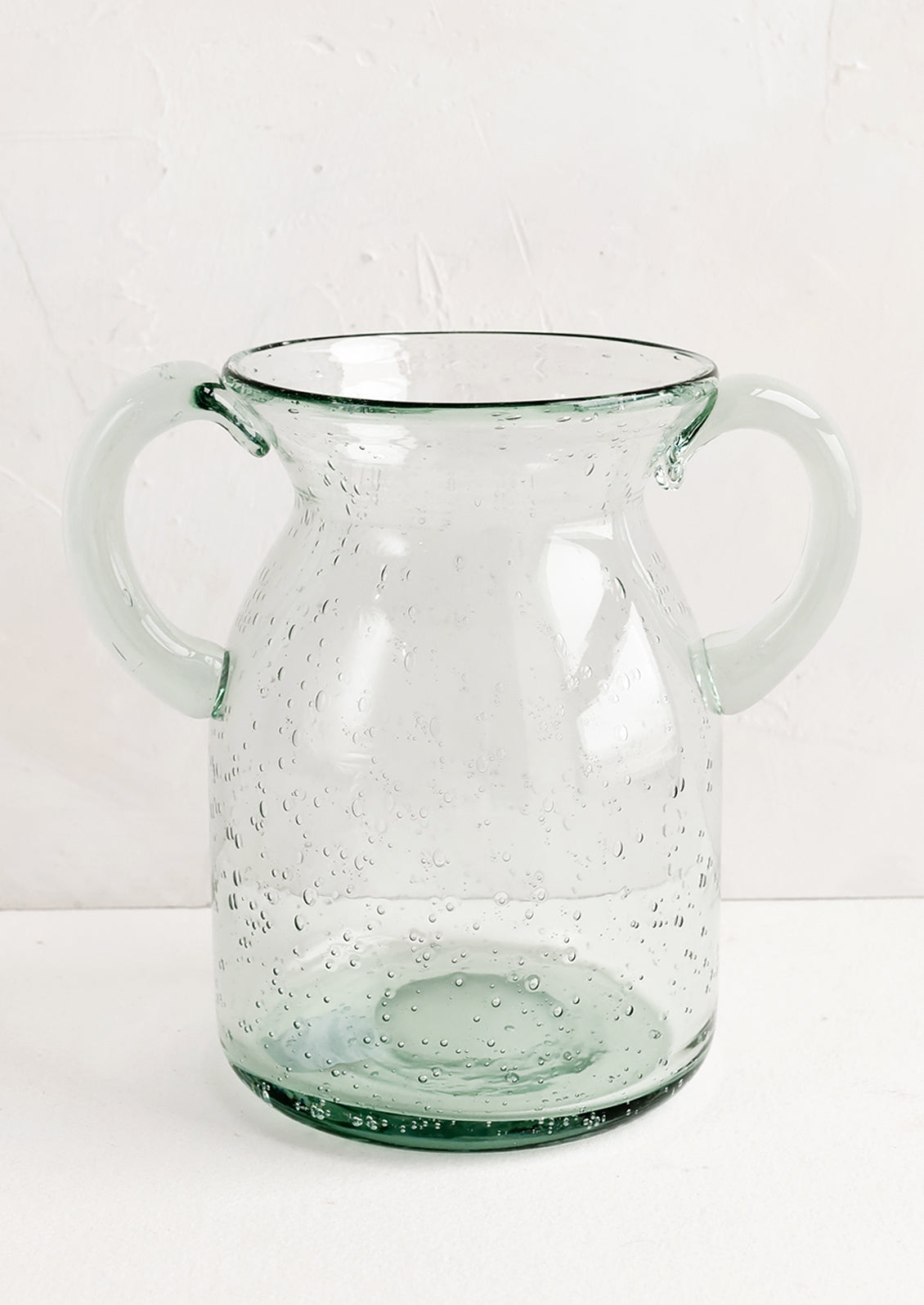 A clear, jug-shaped glass vase.