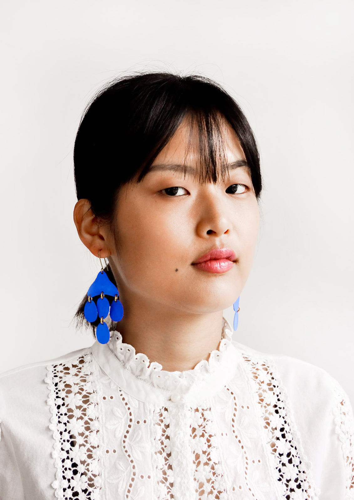 Model shot showing woman wearing earrings and a white top.