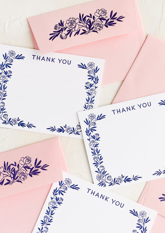 A set of white flat notecards with peony border and "Thank you" written at top.