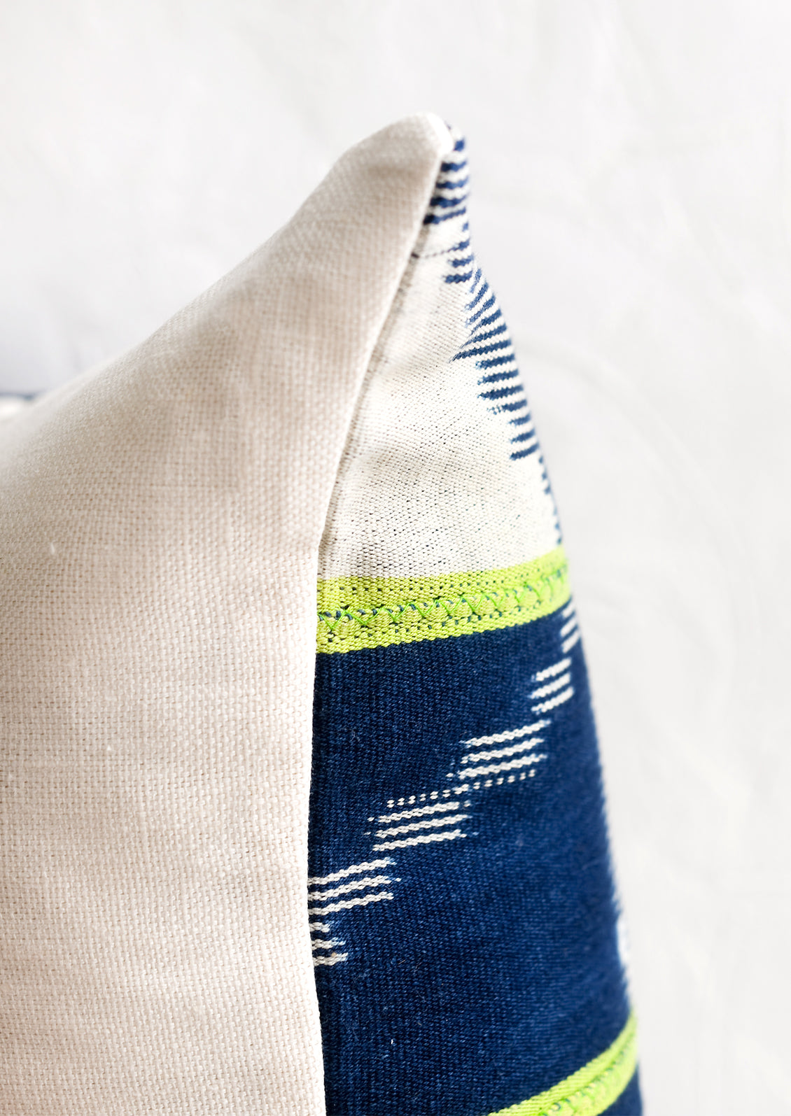 A vintage indigo baule fabric pillow in dark indigo with lime green stripes.