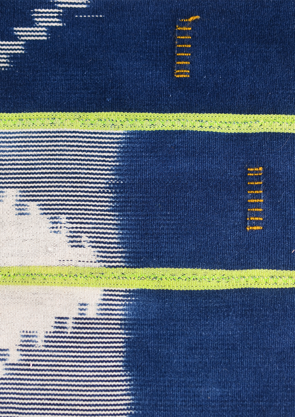 A vintage indigo baule fabric pillow in dark indigo with lime green stripes.
