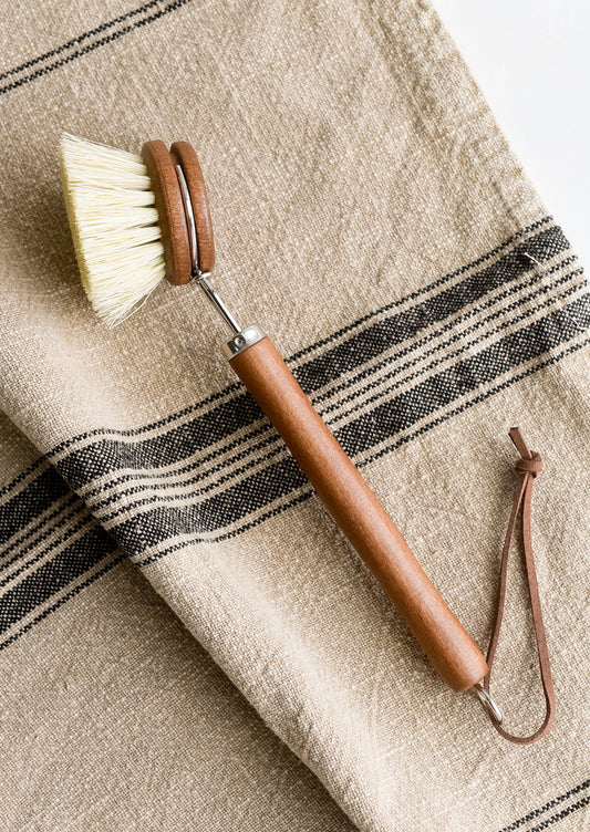 A round headed dish brush with handle in brown beech.