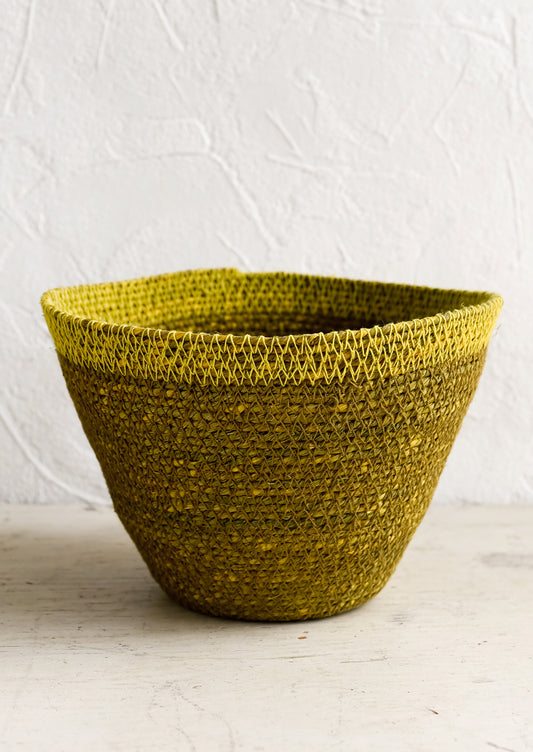 A tapered seagrass storage basket in ochre with yellow rim.