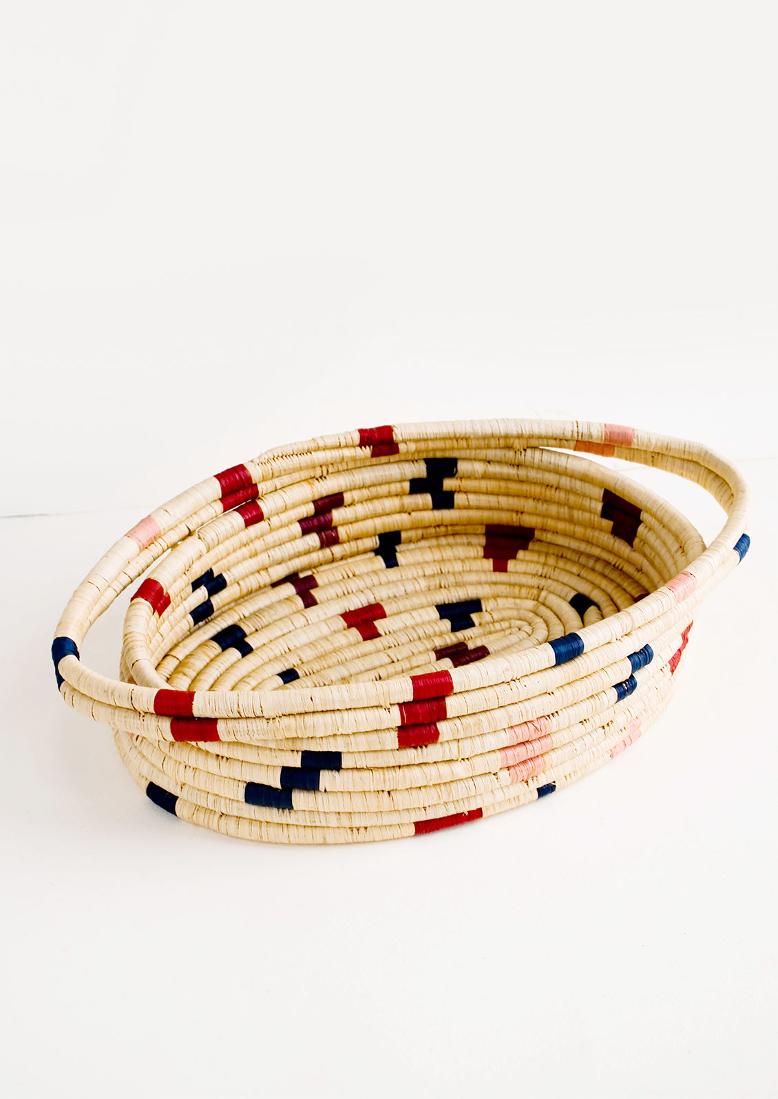 Oval shaped, woven raffia basket with terrazzo inspired print in shades of wine