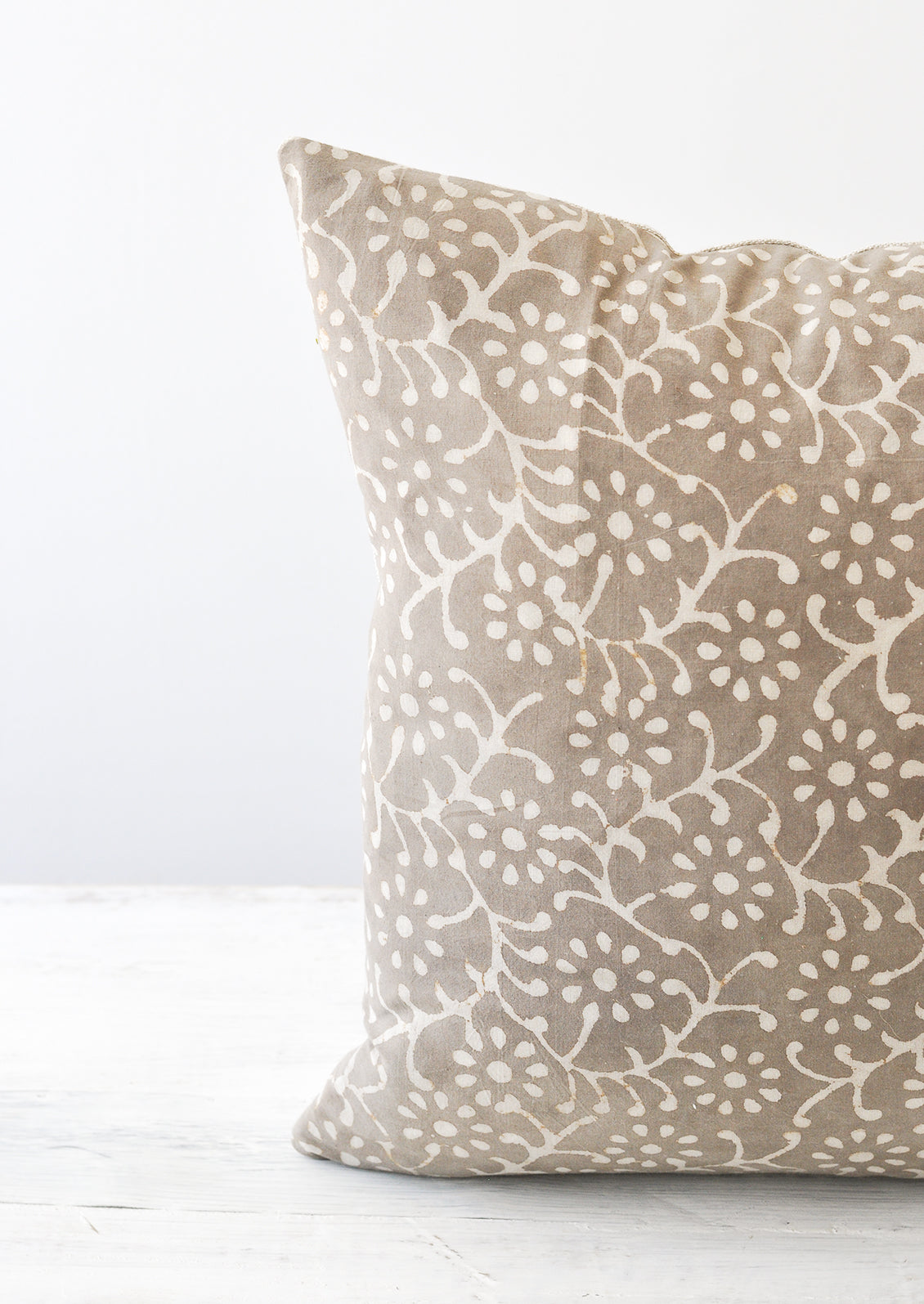 Detail shot of a grey and white floral block-printed square pillow.